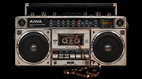 An old Aiwa radio cassette recorder, tape spilling out of the deck